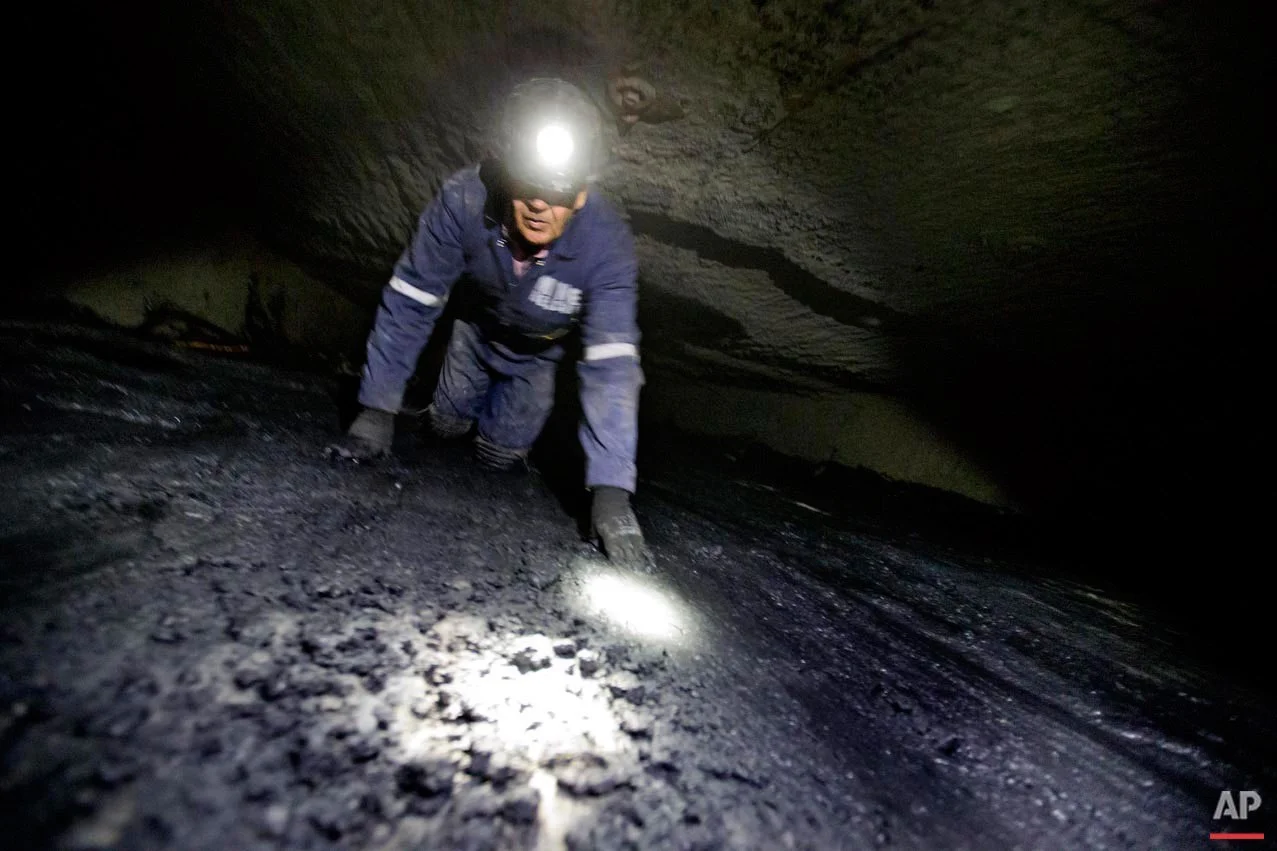 In this Oct. 6, 2015 photo Donnie Coleman, chief safety director and a coal miner of almost 40 years, crawls through the Sally Ann 1 underground coal mine roughly 40-inches-high in Welch, W.Va. (AP Photo/David Goldman)