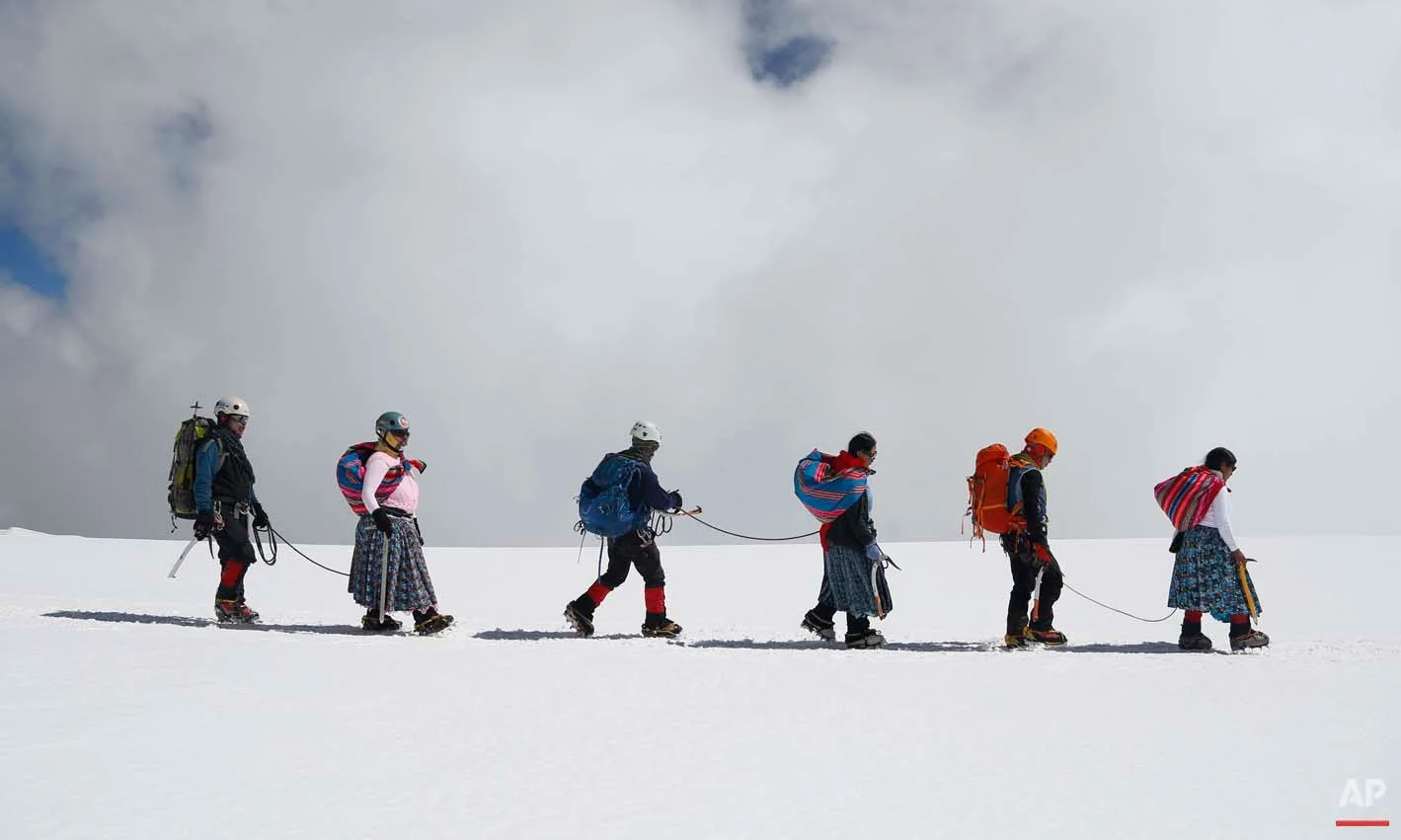 In this Dec. 17, 2015 photo, Aymara indigenous women descend the Huayna Potosi mountain with their husbands, who work as professional guides, on the outskirts of El Alto, Bolivia. Eleven women, ranging in age from 20 to 50 years old, made the two-day climb up the mountain. All of the women work as porters and cooks at the base camp, but six of the youngest ones would like to eventually join the ranks of the men and guide tourists to the peak. (AP Photo/Juan Karita)