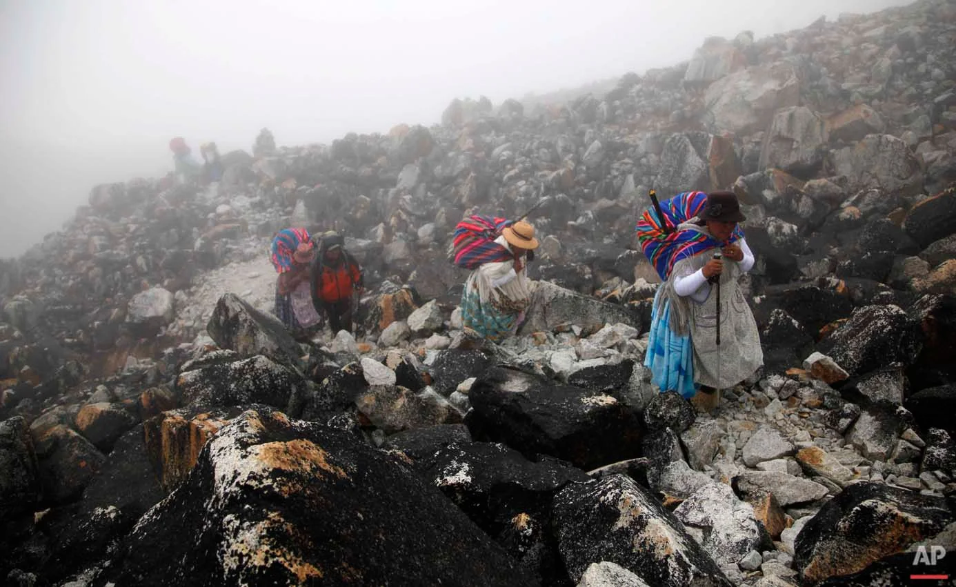 In this Dec. 16, 2015 photo, Aymara indigenous women walk through the fog with their guide, up the Huayna Potosi mountain on the outskirts of El Alto, Bolivia. As they climb, the women wear thermal sweat suits under their traditional "cholita" clothing. Only in the last part of the climb up to the top do the women remove their skirts, to prevent accidents. (AP Photo/Juan Karita)