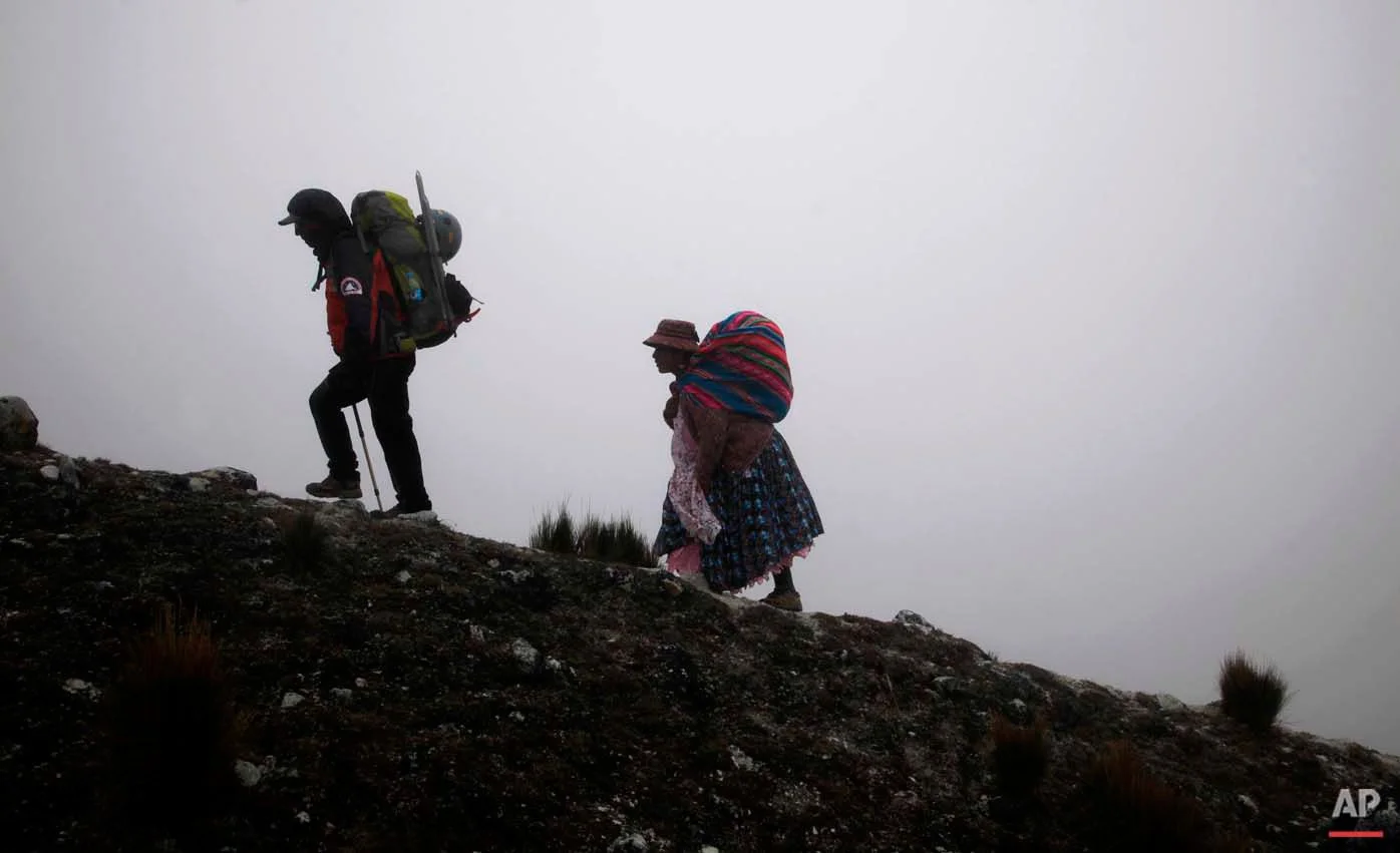 In this Dec. 16, 2015 photo, Aymara indigenous woman Cecilia Llusco Alana, right, follows her guide as they hike up the Huayna Potosi mountain on the outskirts of El Alto, Bolivia. They started the last piece of their ascent after midnight to take advantage of the hardness of the snow, hoping to reach the top by dawn. (AP Photo/Juan Karita)
