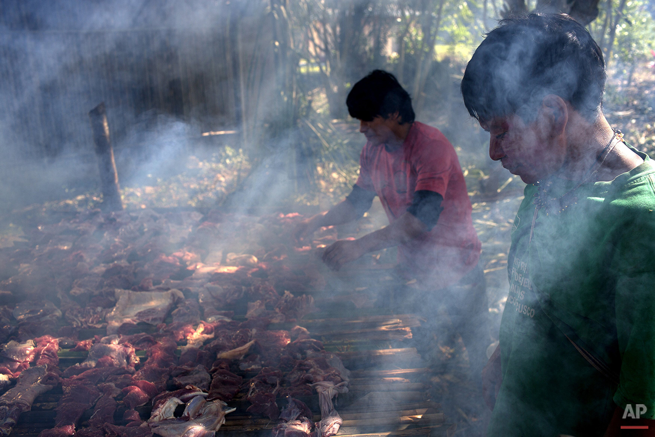  In this June 22, 2015 photo, Ashaninka Indian men smoke meat on a grill made from bamboo canes, in the Otari Nativo village, Pichari, Peru. The strips of meat come from a cow that was donated by municipal authorities to mark the 44th anniversary of 