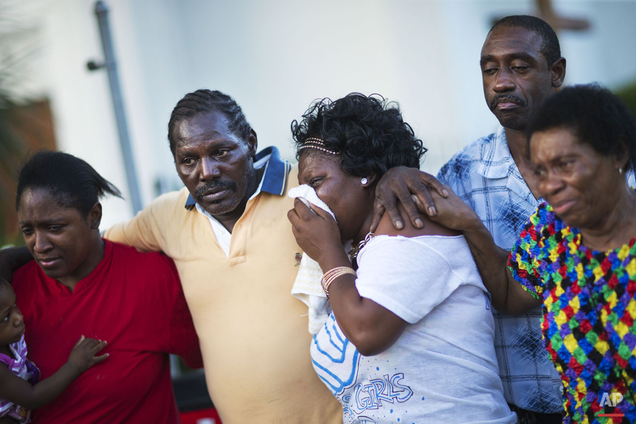 Gary and Aurelia Washington, center left and right, the son and granddaughter of Ethel Lance who died in Wednesday's shooting, leave a sidewalk memorial in front of Emanuel AME Church comforted by fellow family members Thursday, June 18, 2015, in Charleston, S.C. (AP Photo/David Goldman)