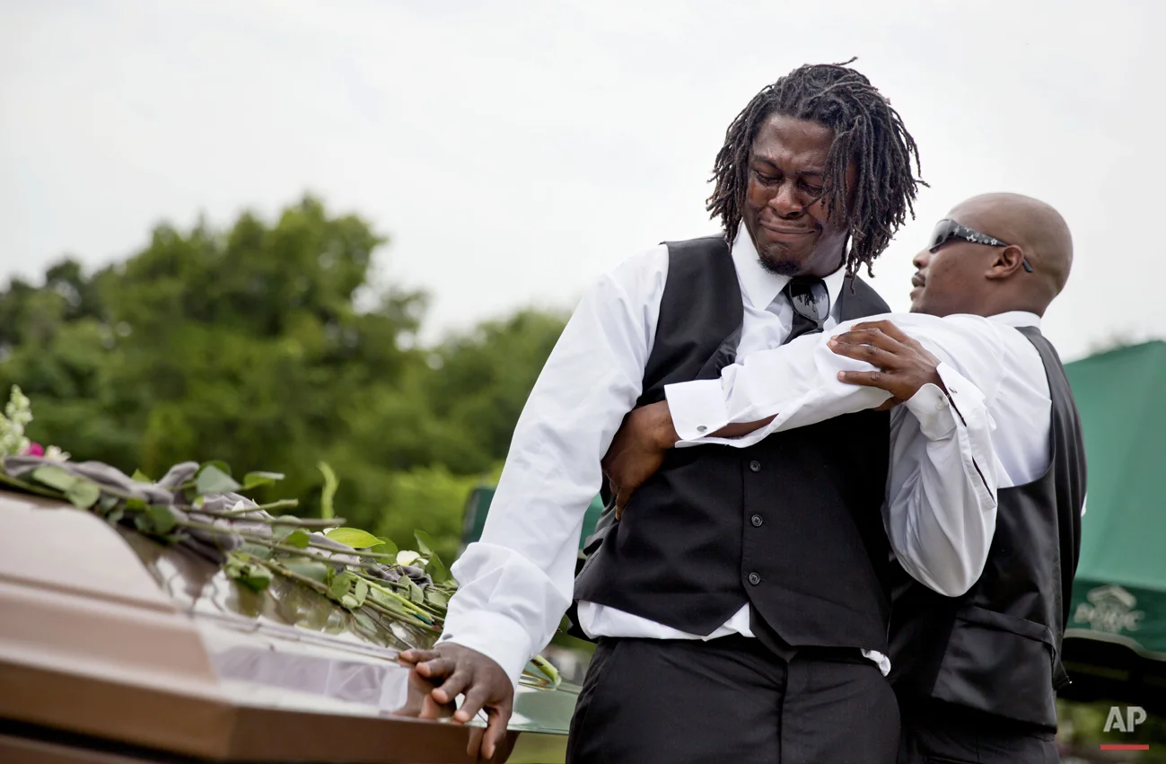 Brandon Risher, left, is pulled away by a friend as he cries over the casket of his grandmother, Ethel Lance, following her burial service, the first one for the nine people killed in the shooting at Emanuel AME Church, Thursday, June 25, 2015, in Charleston, S.C. (AP Photo/David Goldman)