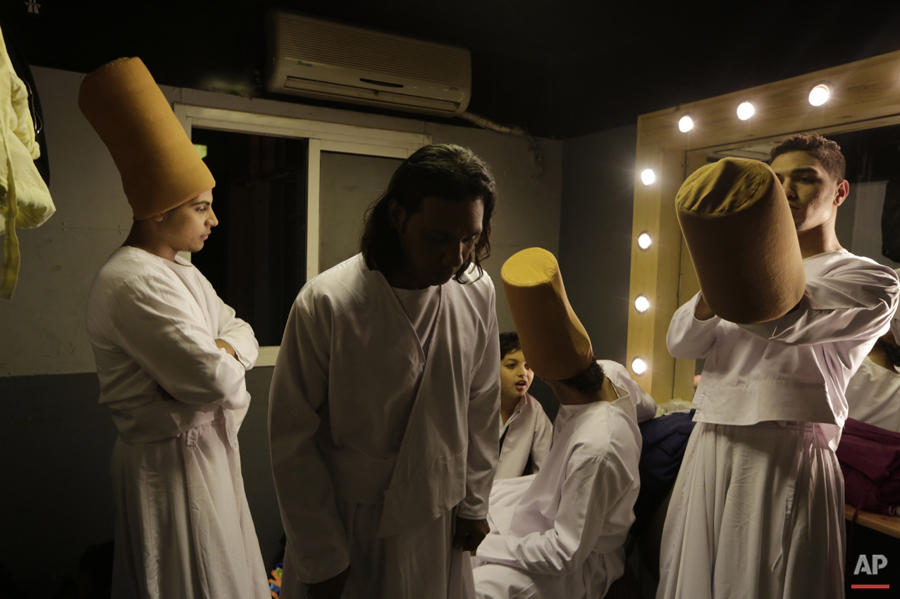 In this Thursday, April 23, 2015 photo, whirling dervish Sayed Abdel Basir, center, a member of the Al-Tannoura Egyptian Heritage Dance Troupe, prays inside a dressing room, before the group performs at the El Sawy cultural center in Cairo, Egypt. (AP Photo/Amr Nabil)