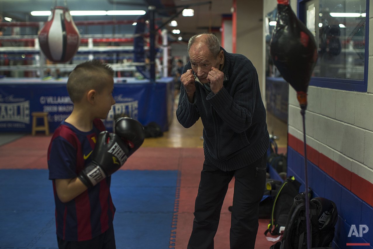  In this Monday, April 25, 2016 photo, boxing coach Manolo del Rio, right, talks to his young pupil Mario Andres Ciobanu, 8, during a training session at El Rayo boxing gym in Madrid. (AP Photo/Francisco Seco) 