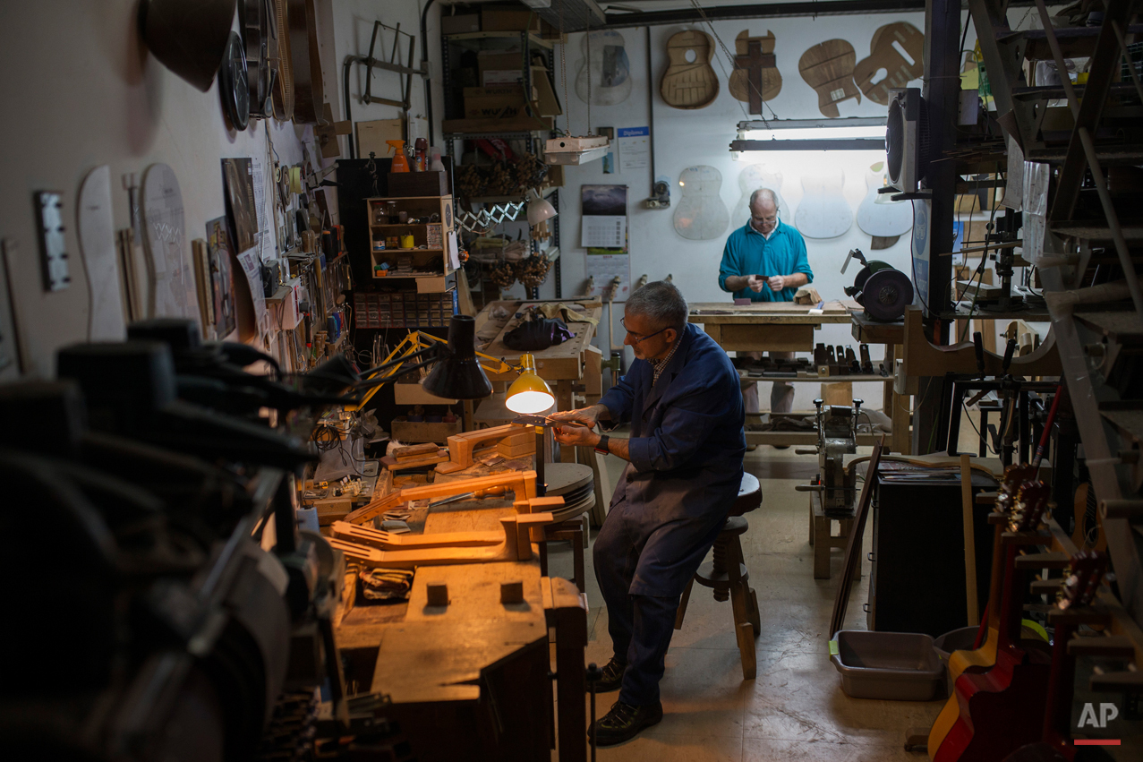  In this Tuesday, Nov. 10, 2015 photo, two Spanish guitar makers work at a workshop in Madrid. Spanish flamenco guitars are known for their beautiful shape, rich wood colors and full-bodied, crisp musical tones. (AP Photo/Francisco Seco) 