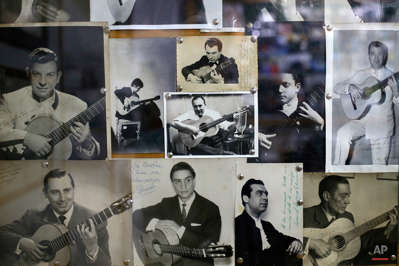  In this Wednesday, Nov. 11, 2015 photo,  photos of Spanish 'flamenco' guitar players are pinned to the wall at a guitar workshop in Madrid. Spanish flamenco guitars are known for their beautiful shape, rich wood colors and full-bodied, crisp musical