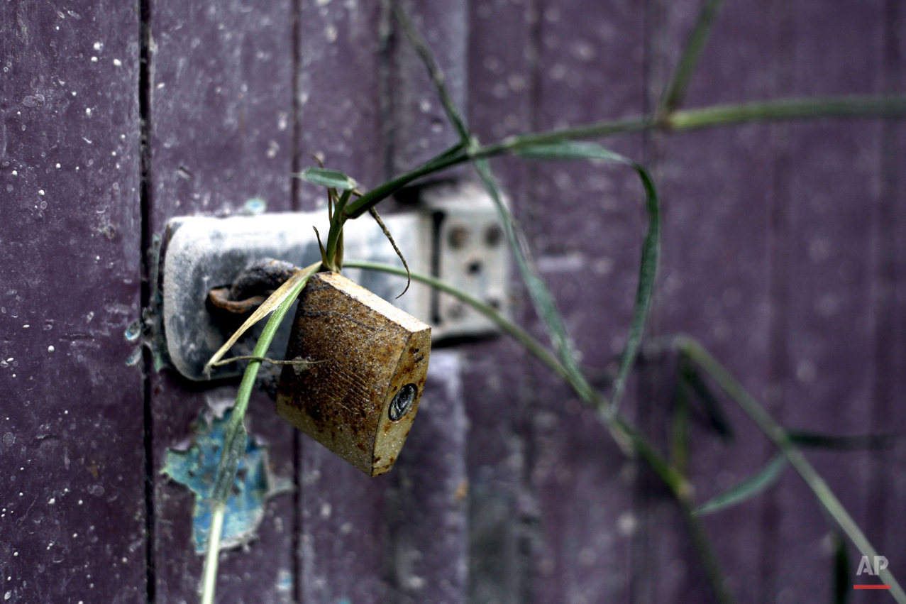  In this Friday, Nov. 13, 2015 photo, the door of a barn is seen secured with a weathered padlock in the village of Guru Kinayan which was abandoned following the eruption of Mount Sinabung, in North Sumatra, Indonesia. Crumbling buildings and person