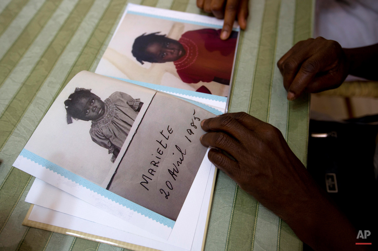  In this July 13, 2015 photo, during a visit with her birth mother and other family, in Port-au-Prince, Haiti, adoptee Mariette Williams shows pictures of herself, made when she was living at a Haitian orphanage in the mid 80's. For the first time in