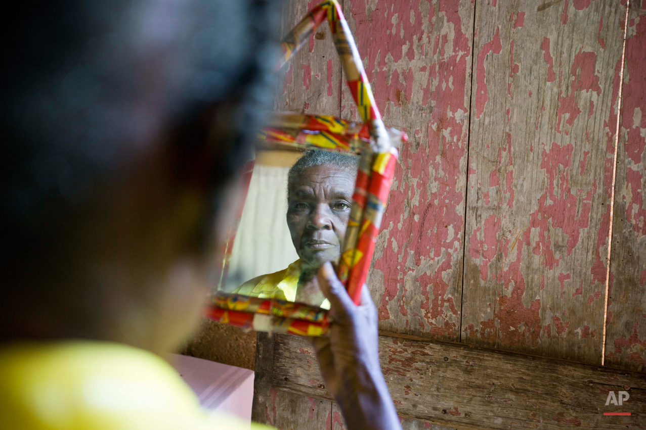  ADVANCE FOR FRIDAY, NOV. 27, 2015, AND THEREAFTER - In this July 15, 2015 photo, Colas Etienne looks at her reflection inside her home in Deron, a neighborhood on the outskirts of Pestel, Haiti. Colas Etienne was a shadow at the very edge of Mariett