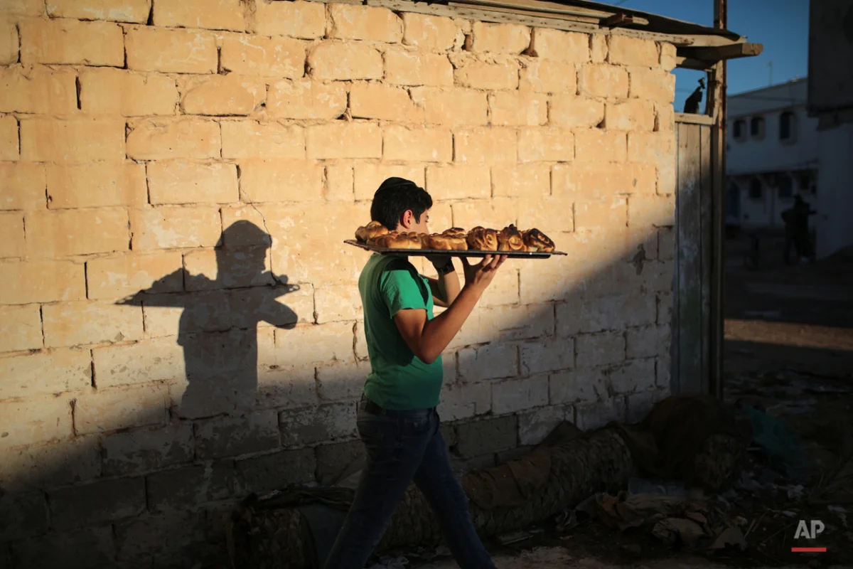  In this Friday, Oct. 30, 2015 photo, a boy heads home with freshly baked Challah, a special Jewish bread, at the beginning of Shabbath, at Hara Kbira, the main Jewish neighborhood on the Island of Djerba, southern Tunisia. The Jewish community in th