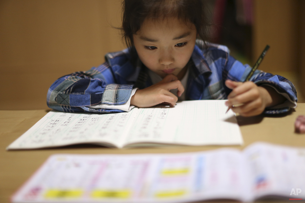  In this Nov. 18, 2015 photo, 9-year-old Mahiro Takano, three-time Japan karate champion in her age group, does her school homework's at home before going to her karate practice in Nagaoka, Niigata Prefecture, north of Tokyo.  Mahiro stars in singer 