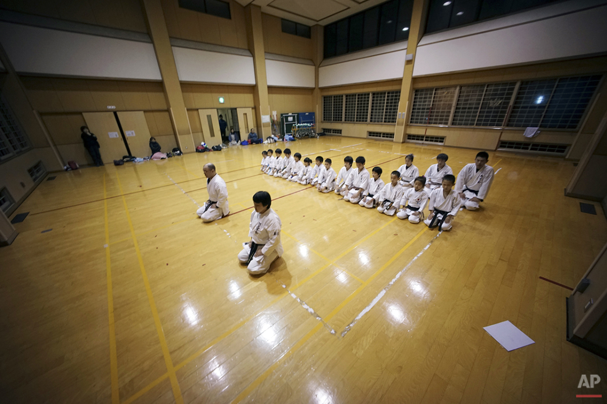  In this Nov. 18, 2015 photo, 9-year-old Mahiro Takano, second from right in middle row, three-time Japan karate champion in her age group sits straight with other fellow karate students at the end of day's practice session in Nagaoka, Niigata Prefec