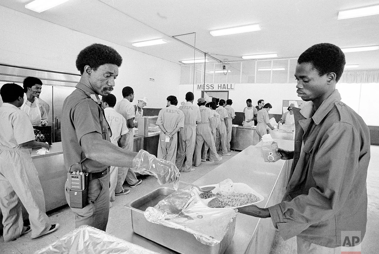 An inmate at the Krome North Service Processing Center is served lunch by a prison employee, March 4, 1985. The prison, located west of Miami, has been called the "Caribbean Ellis Island." it houses 523 people who were apprehended trying to enter the United States illegally. (AP Photo/Raul de Molina)