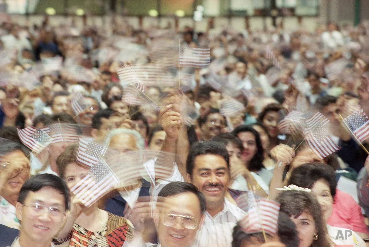 New U.S. citizens wave their flags with excitement during a naturalization ceremony, Wednesday, August 14, 1996 in Los Angeles. Thirty thousand people were naturalized over the past three days in Los Angeles and immigration officials expect 320,000 candidates to becomes U.S. citizens this year in Los Angeles. (AP Photo/Frank Wiese)