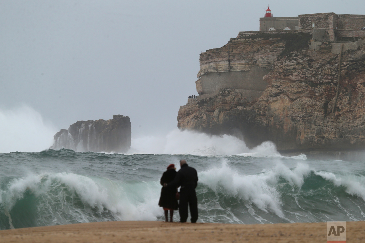 A couple watches the waves break on the coastline in Nazare, Portugal, Thursday, Feb. 2, 2017, as strong winds hit the area. (AP Photo/Armando Franca)