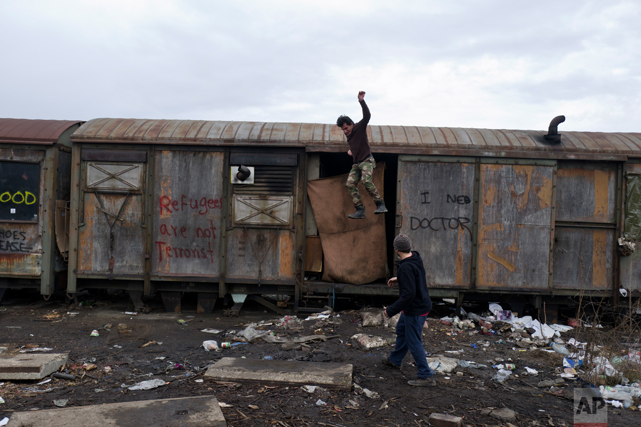An Afghan refugee jumps off an old train carriage where he and others took refuge in Belgrade, Serbia, Friday, Feb. 3, 2017. Hundreds of migrants have been sleeping amid in freezing temperatures in central Belgrade looking for ways to cross the heavily-guarded EU borders. (AP Photo/Muhammed Muheisen)