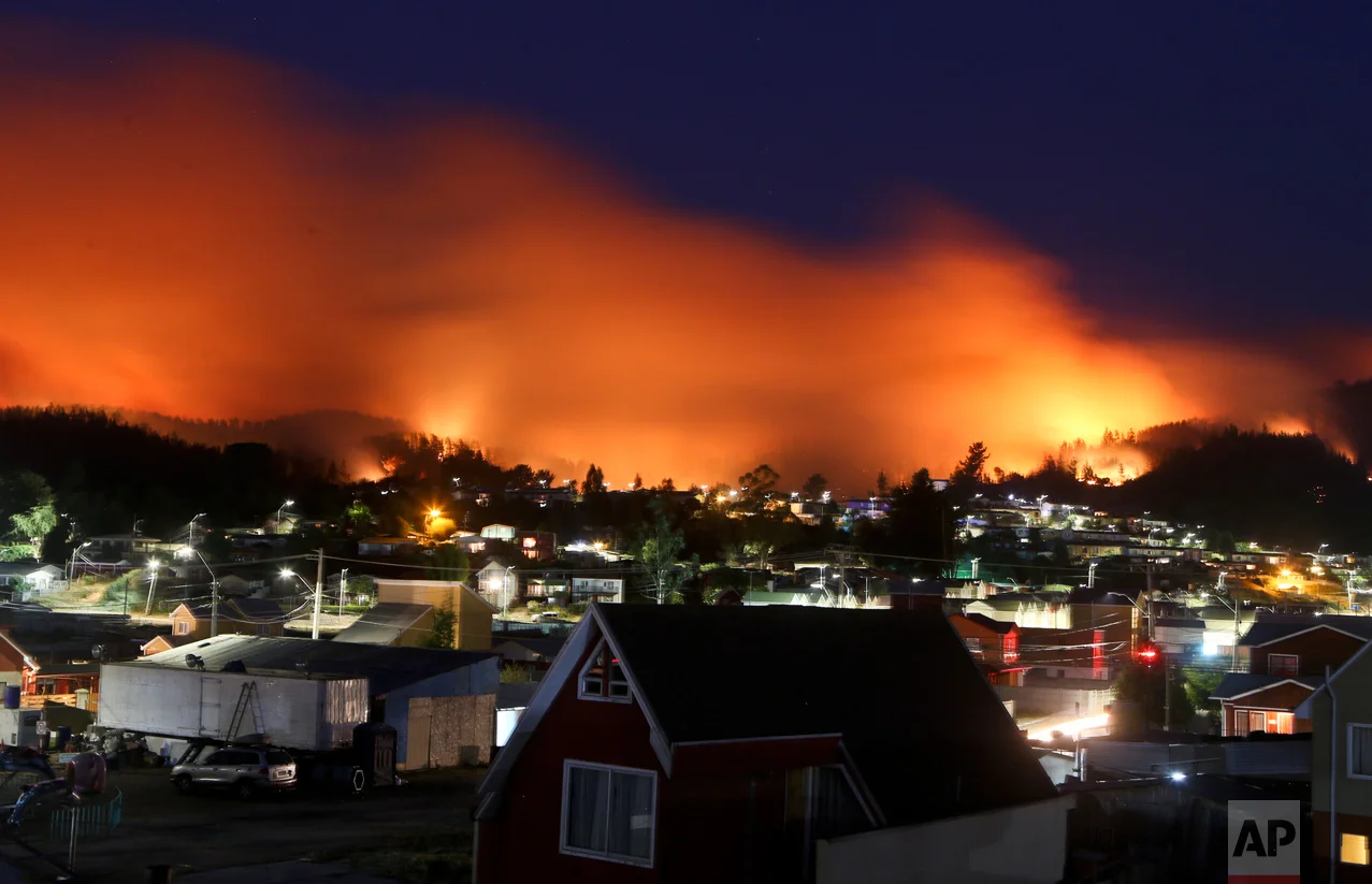 A wildfire approaches Chile's Dichato community, Monday, Jan. 30, 2017, where firefighters are working to keep the flames away from the estimated 800 homes. The fires have consumed forests, livestock and entire towns, prompting President Michelle Bachelet to declare a state of emergency, deploy troops and ask for international help. (AP Photo/Esteban Felix)