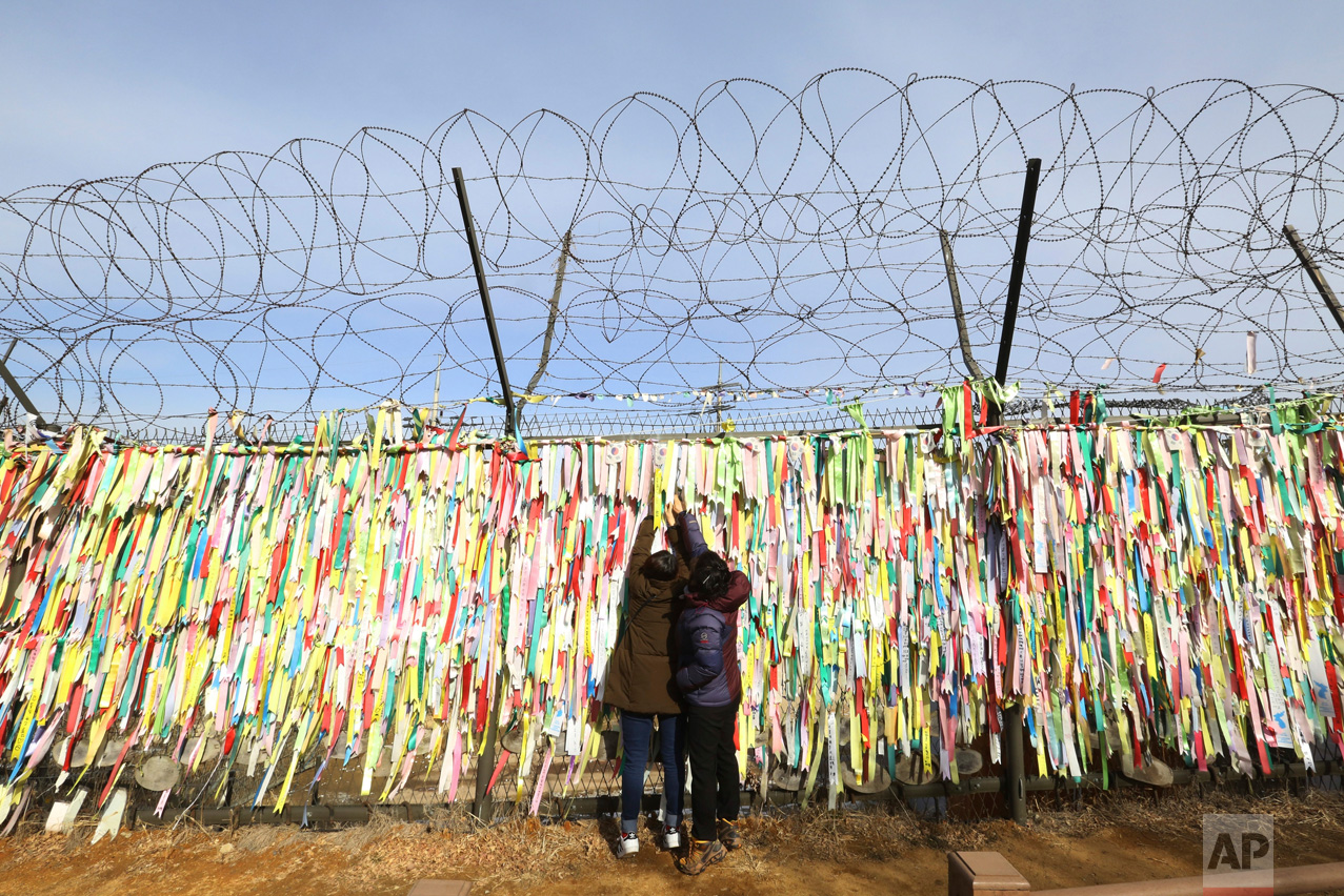 Women hang a ribbon wishing for the reunification of the two Koreas on a fence as they celebrate the Lunar New Year at the Imjingak Pavilion, near the demilitarized zone of Panmunjom, in Paju, South Korea, Saturday, Jan. 28, 2017. Millions of South Koreans visit their hometowns during the four-day holiday. (AP Photo/Ahn Young-joon)