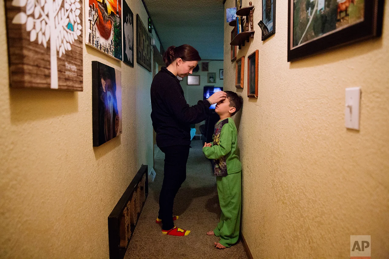 Lydia Holt, left, talks her stepson, Carter, 7, into going to bed at their home in Wauzeka, Wis., Tuesday, Jan. 17, 2017. Holt, who makes $400 a week as an assistant at a law firm and whose husband doesn't do much better at a car parts store, worry that by the time their sons grow up there will be nothing left for them here. (AP Photo/David Goldman)