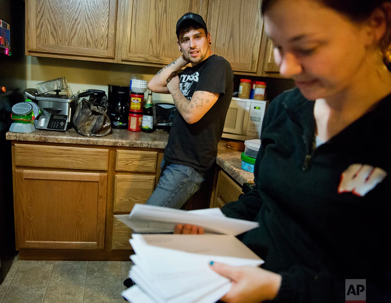 Kreig Holt, left, looks on as his wife, Lydia, flips through envelopes, each containing money for the each of the monthly bills they have to pay, as they stand in their kitchen in Wauzeka, Wis., Tuesday, Jan. 17, 2017. They both earn about $10 an hour and, with two kids, there's always one or two they have to skip. She did the math; at this rate, they'll be paying these same bills for 87 years. In 2012, Lydia Holt voted for Barack Obama because he promised her change, but she feels that change hasn't reached her here. So in 2016, she chose Donald Trump. (AP Photo/David Goldman)