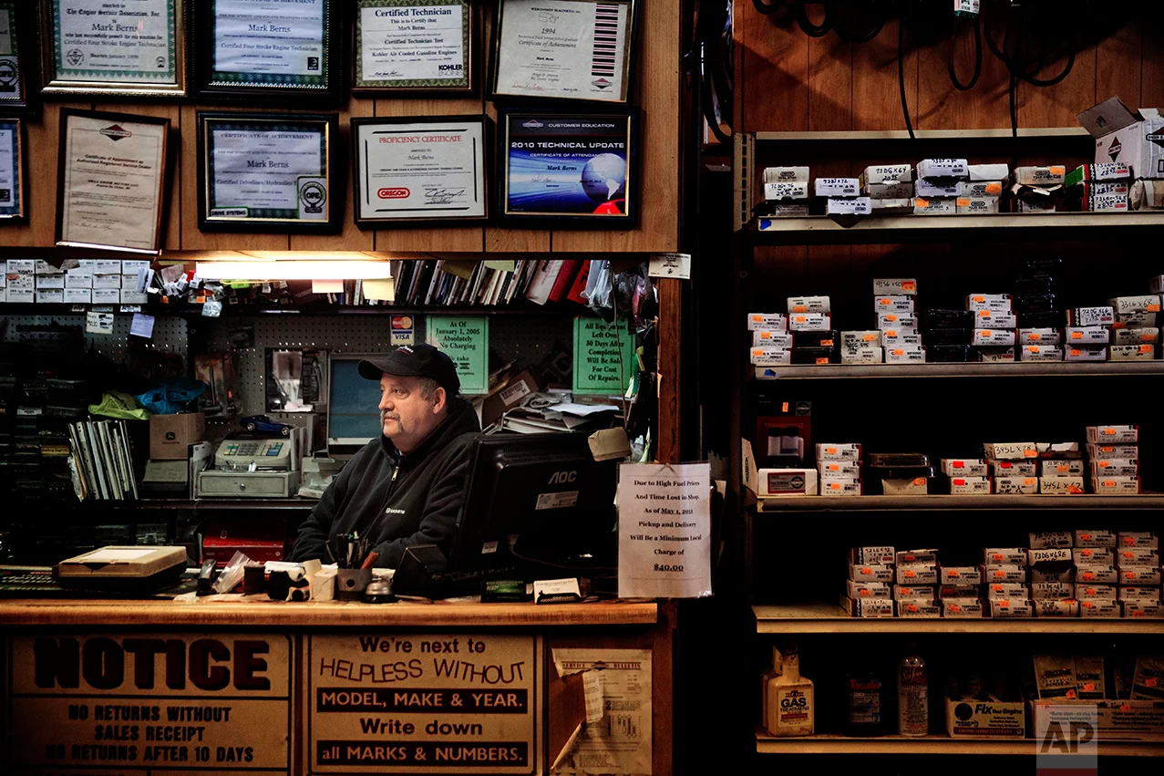 Mark Berns sits in his small engine repair shop in Prairie du Chien, Wis., Thursday, Jan. 19, 2017. "If you ask anybody here, we'll all tell you the same thing: We're tired of living like this. We've been railroaded, run over by the politicians and run over by laws," said Berns in the shop he can barely afford to keep open anymore. He drives a 14-year-old truck with 207,000 miles on it because he doesn't make enough profit to buy a new one. Berns watched Trump's first days in office half-hopeful, half-frightened about the future but said he's willing to give him the benefit of the doubt. (AP Photo/David Goldman)