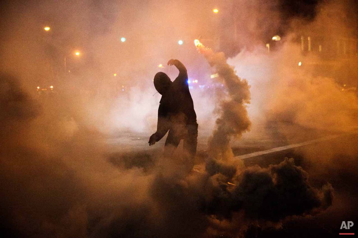  A protestor throws a tear gas canister back toward riot police after a 10pm curfew went into effect in the wake of Monday's riots following the funeral for Freddie Gray, Tuesday, April 28, 2015, in Baltimore. (AP Photo/David Goldman) 