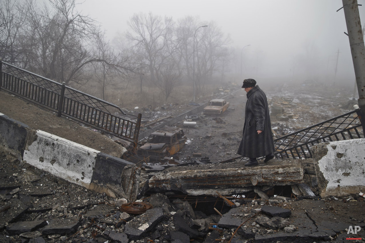  An elderly woman walks on a destroyed bridge on the road to the airport which was the scene of heavy fighting, on her way to retrieve belongings from her home, in Donetsk, Ukraine, Sunday, March 1, 2015.  (AP Photo/Vadim Ghirda) 