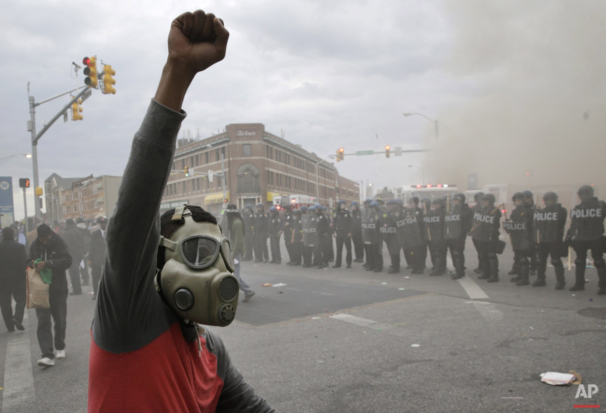 A demonstrator raises his fist as police stand in formation as a store burns, Monday, April 27, 2015, during unrest following the funeral of Freddie Gray in Baltimore. (AP Photo/Patrick Semansky) 