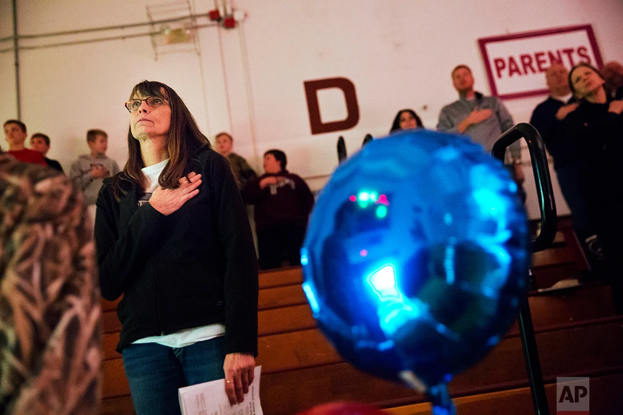 Marlene Kramer stands for the national anthem while watching her stepdaughter cheerlead at a high school wrestling meet in Prairie du Chien, Wis., Thursday, Jan. 19, 2017. Kramer, who voted twice for Obama, used to watch Trump on "Celebrity Apprentice." "I said to myself, ugh, I can't stand him." And when he announced his candidacy, she thought it was a joke. "Then my husband said to me, 'Just think, everything he touches seems to turn to money,'" she said, and she changed her mind. "I'm hoping he'll make this country really rich." (AP Photo/David Goldman)