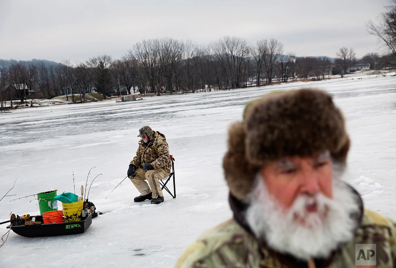 Mark Kleinow, background, ice fishes with his friend Rick Trudo, foreground, on a frozen portion of the Mississippi River in Prairie du Chien, Wis., Wednesday, Jan. 18, 2017. Trudo voted for Trump and Kleinow voted for Clinton. But the left-right, blue-red vitriol that has cleaved apart the country has not left the same scars here. (AP Photo/David Goldman)
