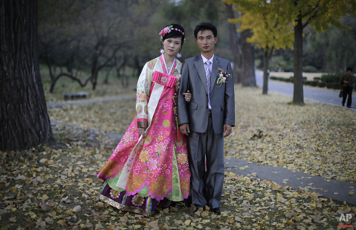  In this photo taken Saturday, Oct. 25, 2014, a North Korean bride and groom pose for a photograph at the Moranbong hill where they went to take wedding pictures, in Pyongyang, North Korea. The couple, Ri Ok Ran, 28 and Kang Sung Jin, 32, were marrie