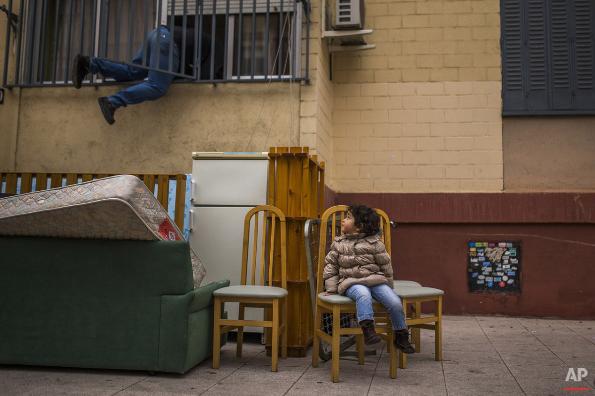  In this picture taken Wednesday, Feb. 11, 2015, Diana Sofia Meliton, 2 years old, sits outside together with belongings after her and her family got evicted by the police and watches a housing right activist re-opening her apartment for them to live