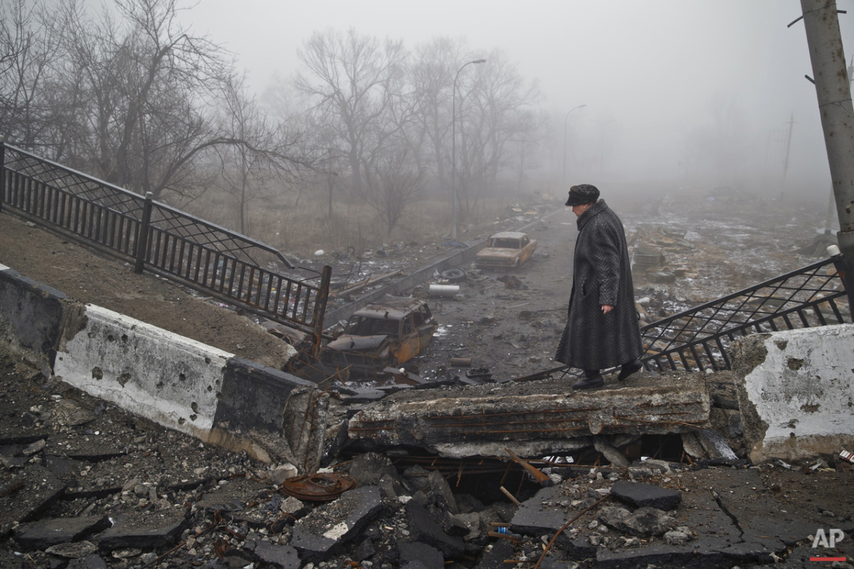  An elderly woman walks on a destroyed bridge on the road to the airport which was the scene of heavy fighting, on her way to retrieve belongings from her home, in Donetsk, Ukraine, Sunday, March 1, 2015. (AP Photo/Vadim Ghirda) 