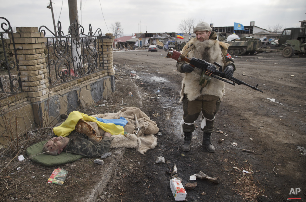  A Russia-backed rebel looks at the flag covered body of an Ukrainian serviceman in Debaltseve, Ukraine, Friday, Feb. 20, 2015. (AP Photo/Vadim Ghirda) 
