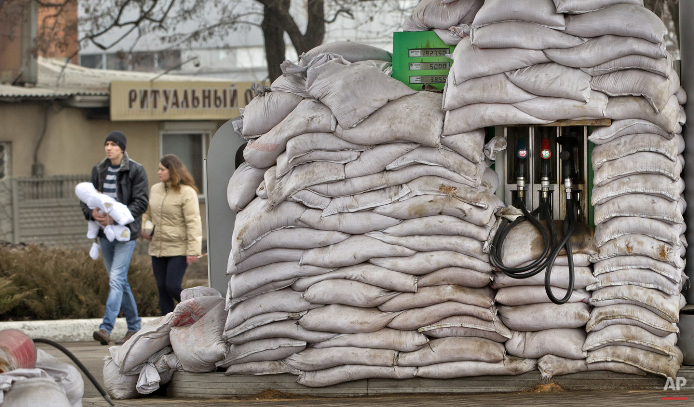  A couple and baby walk past a fuel pump covered in sandbags to protect it from possible shelling, in Donetsk, Ukraine, Monday, March 2, 2015. (AP Photo/Vadim Ghirda) 