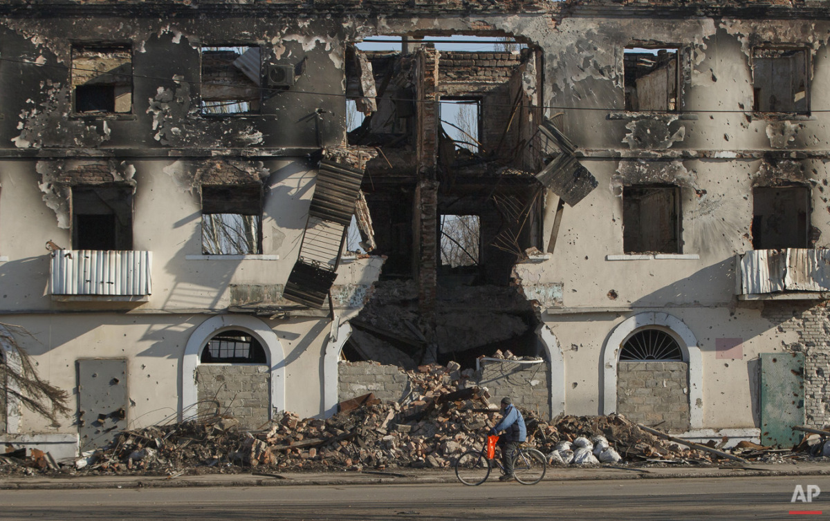  A man rides a bicycle by a destroyed building in Vuhlehirsk, Ukraine, Monday, March 9, 2015. (AP Photo/Vadim Ghirda) 