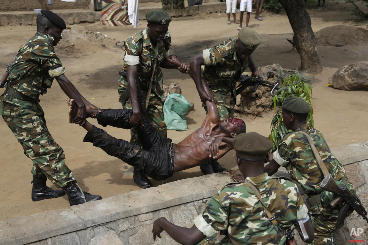  Soldiers lift a wounded suspected Imbonerakure militiaman who was attacked by demonstrators protesting against President Pierre Nkurunziza's decision to seek a third term in office in the Cibitoke district of Bujumbura, Burundi, Thursday May 7, 2015