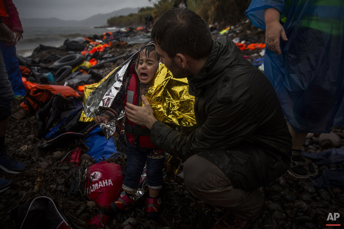  A volunteer tries to calm a child after his arrival with other migrants and refugees on a dinghy from the Turkish coast to the Skala Sykaminias village on the northeastern Greek island of Lesbos, Friday, Oct. 23, 2015. (AP Photo/Santi Palacios) 