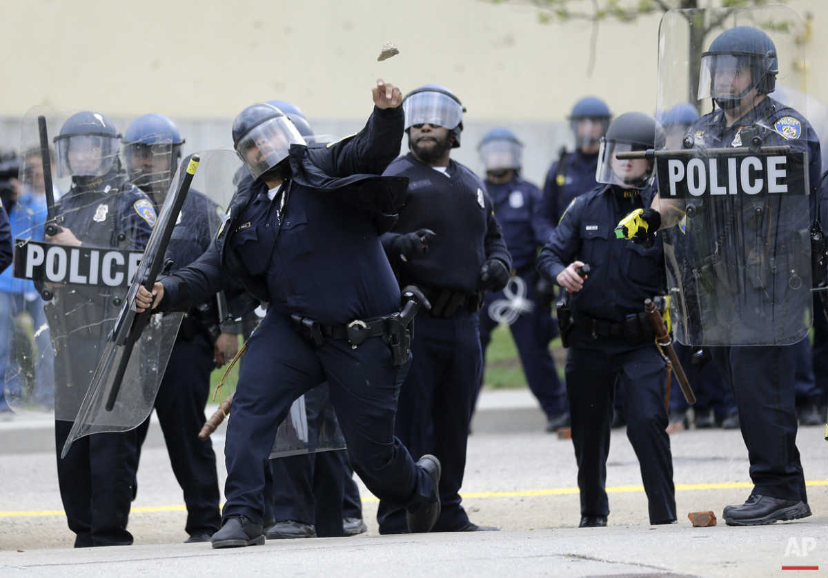  A police officer throws an object at protestors, Monday, April 27, 2015, during unrest following the funeral of Freddie Gray in Baltimore. (AP Photo/Patrick Semansky) 