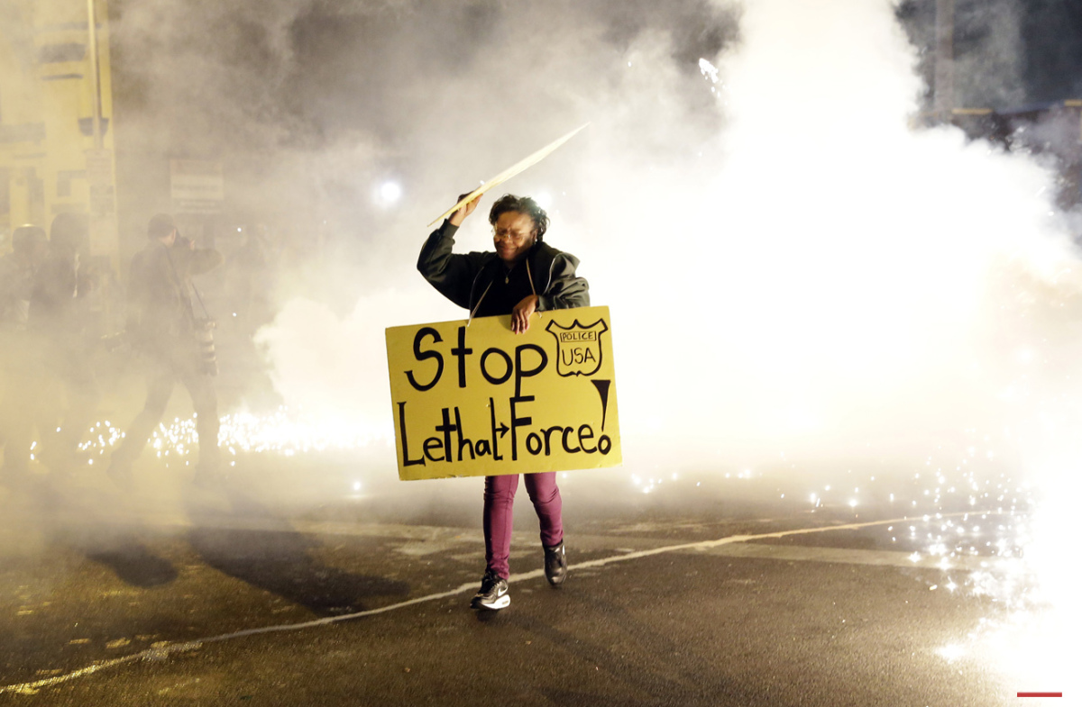  A woman runs for safety as police throw tear gas canisters while enforcing curfew, Tuesday, April 28, 2015, in Baltimore, a day after unrest that occurred following Freddie Gray's funeral. (AP Photo/Patrick Semansky) 