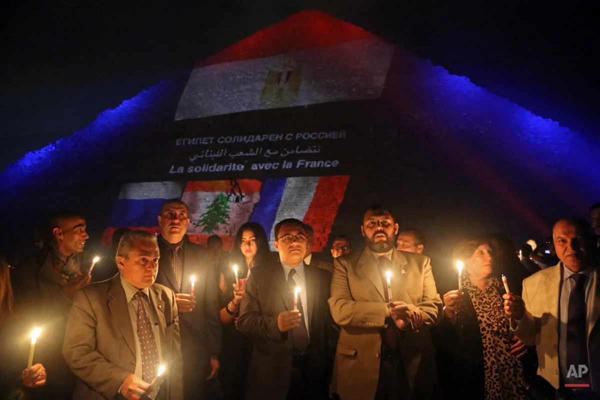 Egyptian tour guides hold a candlelight vigil at the base of the Great Pyramid of Giza in solidarity with victims of attacks in Paris and Beirut and the Russian plane crash in northern Sinai, on the outskirts of Cairo, Egypt, Sunday, Nov. 15, 2015. The Islamic State group have claimed responsibility for Friday night's attacks in Paris, Thursdays's twin powerful suicide bombings that tore through a crowded Shiite neighborhood of Beirut, and bringing down a Russian jetliner over Egypt's Sinai region earlier this month. (AP Photo/Thomas Hartwell)