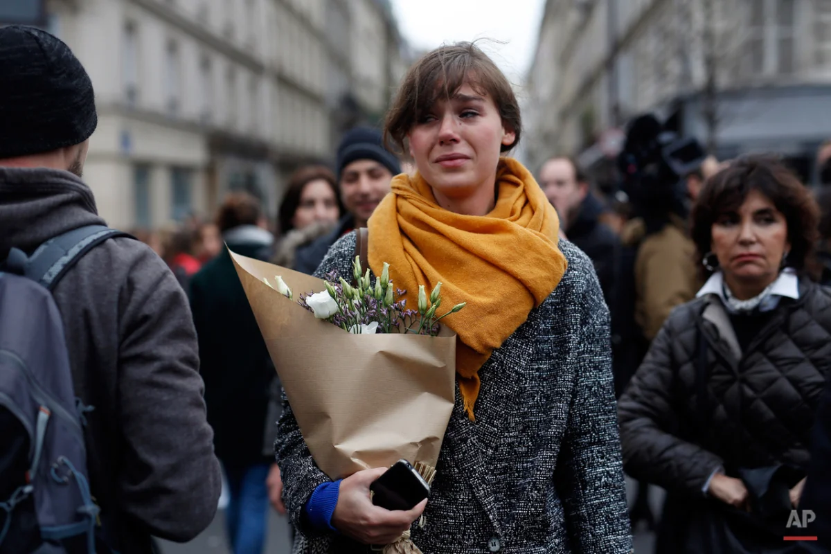 A woman carrying flowers cries in front of the Carillon cafe and the Petit Cambodge restaurant in Paris Saturday Nov. 14, 2015, a day after a series of attacks in Paris. French officials said scores of people died Friday night when attackers launched gun attacks at Paris cafes, detonated suicide bombs near France's national stadium and killed hostages inside a concert hall during a rock show. (AP Photo/Jerome Delay)