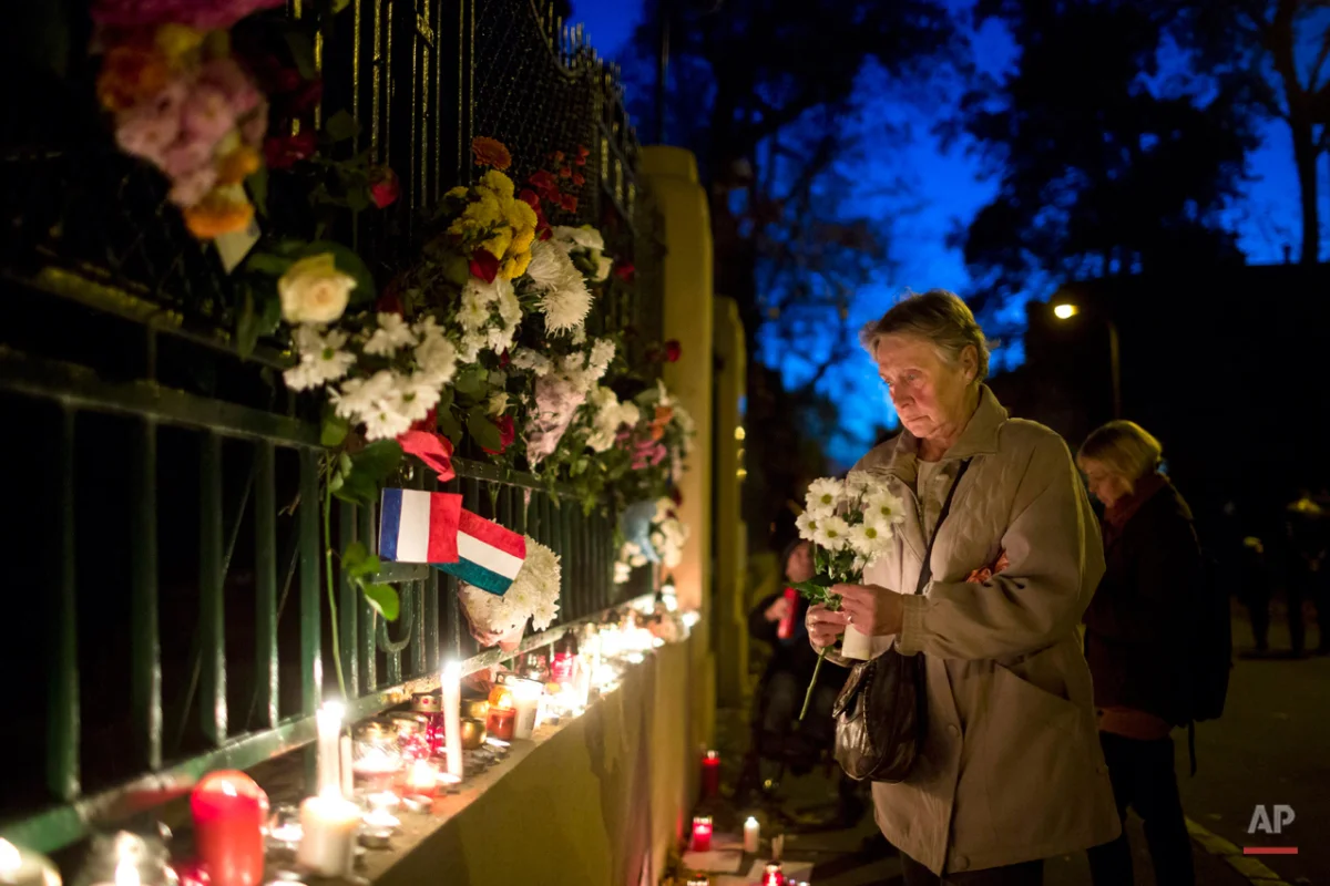 A woman lays flowers to pay tribute to the victims of Paris Attacks outside the French Embassy in Budapest, Hungary, Saturday, Nov. 14, 2015. Multiple attacks across Paris on Friday night have left scores dead and hundreds injured. (Balazs Mohai/MTI via AP)