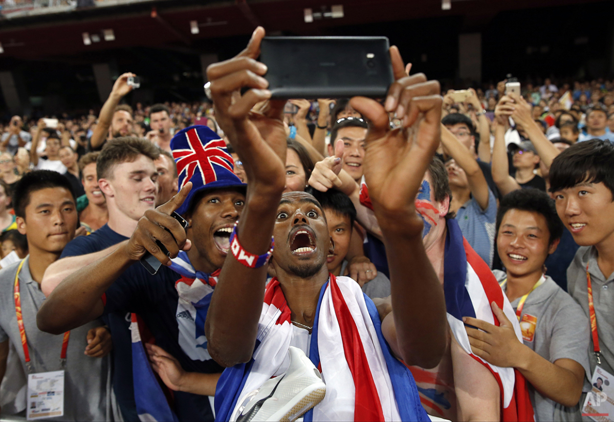  Britain's Mo Farah has a selfie taken with spectators as he celebrates after winning the gold medal in the men's 5000m final at the  World Athletics Championships at the Bird's Nest stadium in Beijing, Saturday, Aug. 29, 2015. (AP Photo/Ng Han Guan)