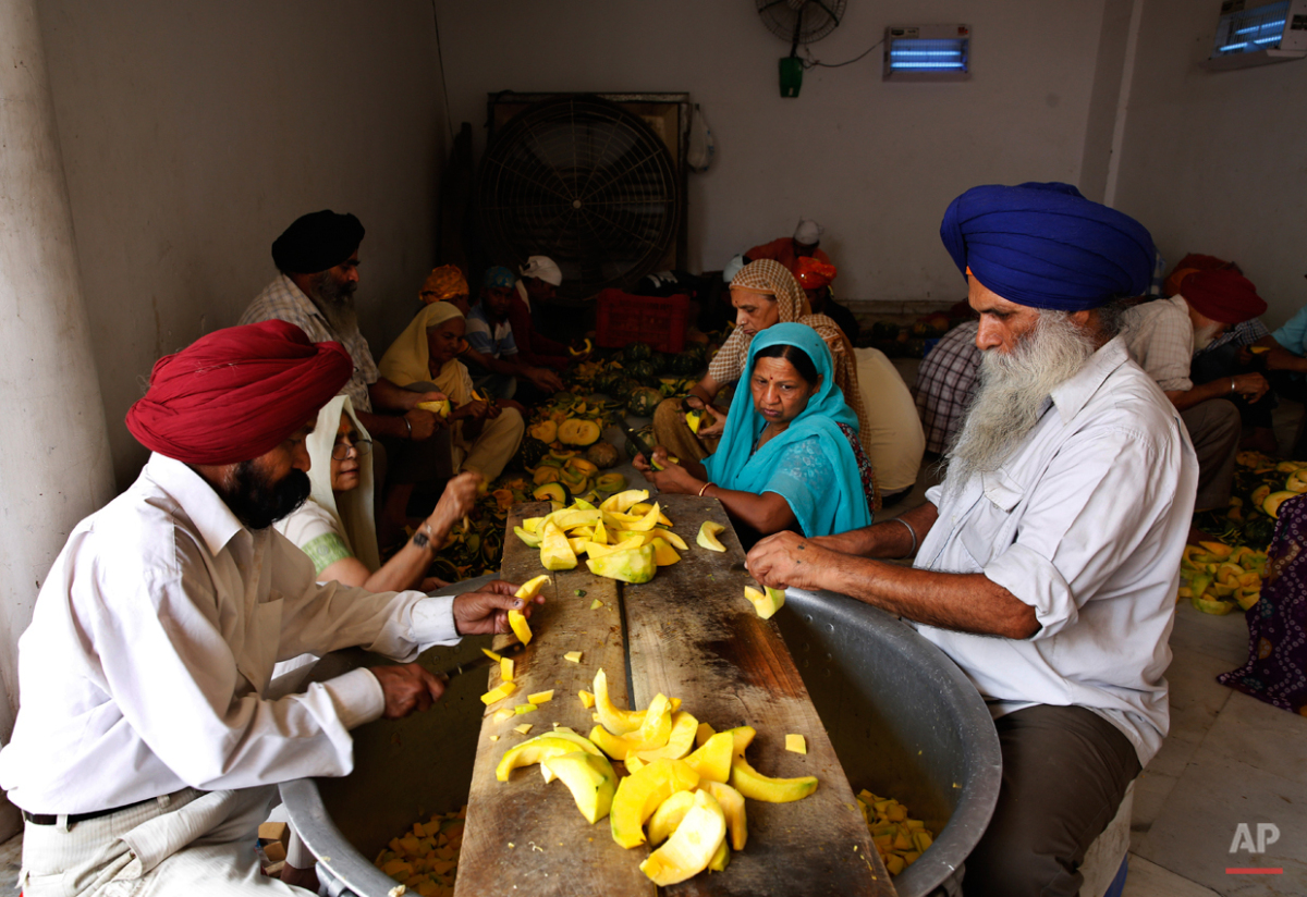 In this May 19, 2015 photo, volunteers and devotees cut vegetables as the prepare langar, which translates to community dinner, at Bangla Sahib Gurudwara or Sikh temple, in New Delhi, India. Service is one of the most integral traditions of gurudwar