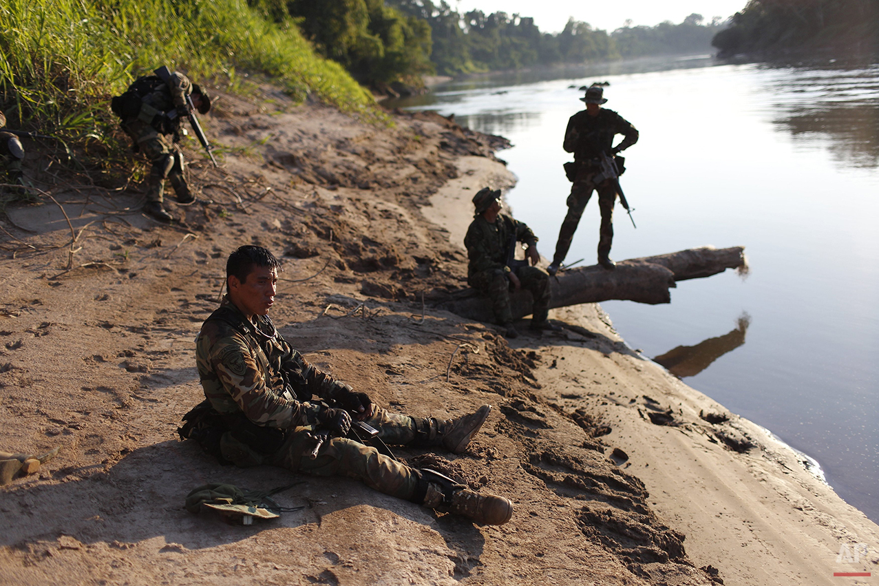  In this July 31, 2015 photo, counternarcotics police officer Merlin Gonzales, 27, takes a break as he sits on the sandy back of the Palcazu River, while he waits with his comrades for the boat that will carry them back to their base in Ciudad Consti