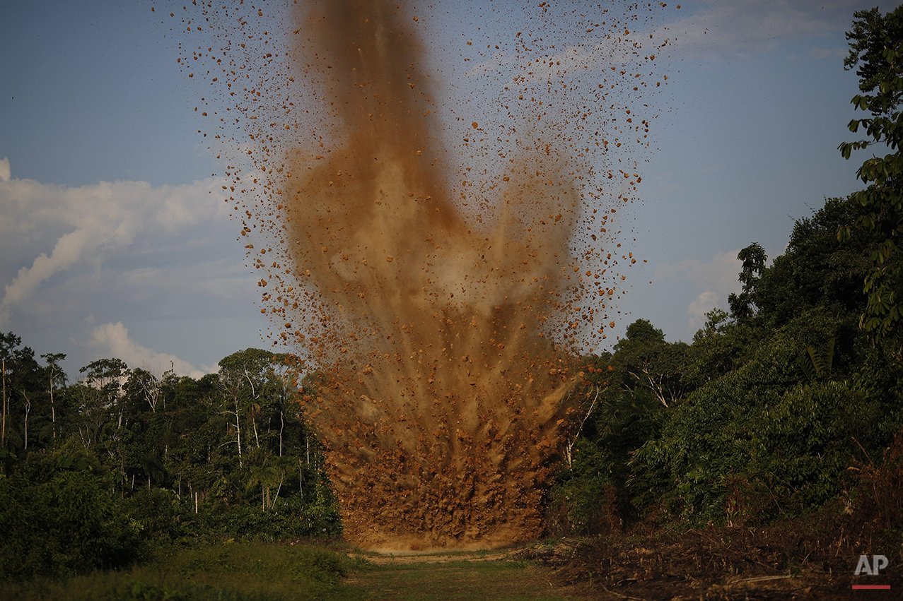  In this July 31, 2015 photo, dirt is blasted skywards as a clandestine airstrip is cratered with explosives by Peruvian counternarcotics forces, in the jungle near Ciudad Constitucion, Peru. According to police, the airstrip is used by drug traffick