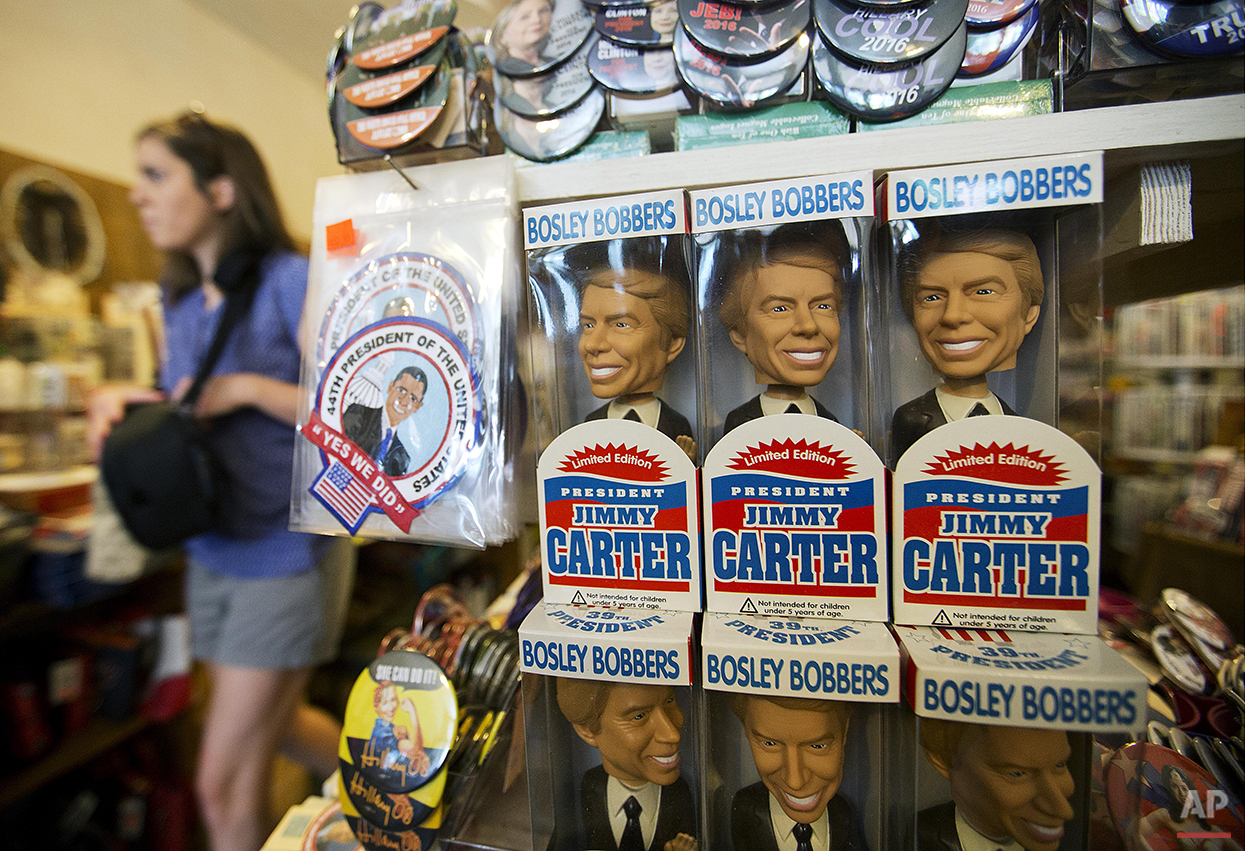 A person walks near dolls of former President Jimmy Carter in a store in his hometown of Plains, Ga., Saturday, Aug. 22, 2015, The one-block business district specializes in Carter political memorabilia and peanut souvenirs. Visitors stop by after t