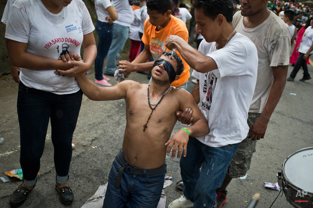  In this Aug. 10, 2015 photo, a ìpromesanteî or devotee of Managua's patron saint, Santo Domingo de Guzman, wearing a blindfold, advances on his knees towards the Las Sierritas parish church, while he is assisted relatives, as a payment for a perceiv